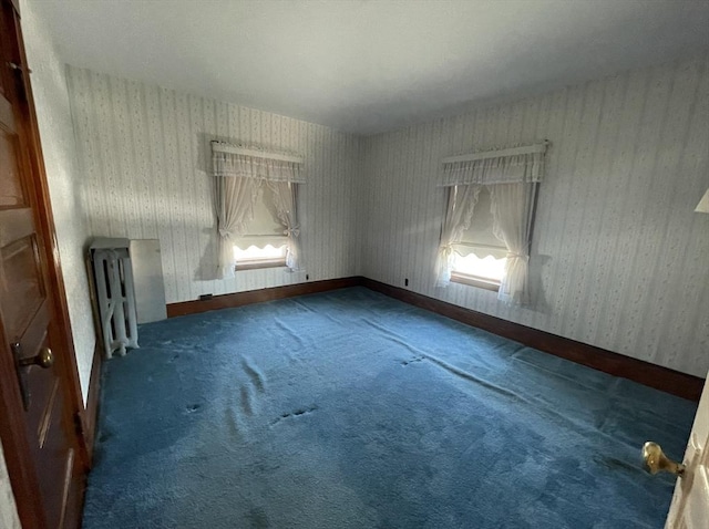 spare room featuring radiator and dark carpet