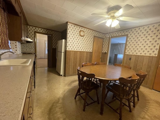 dining room with ceiling fan, sink, and wooden walls