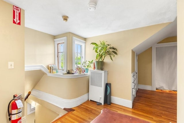 126 W Wyoming Ave, Melrose, MA 02176 - hallway with wood finished floors, baseboards, radiator, and an upstairs landing