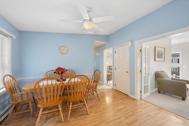 dining space with a baseboard radiator, ceiling fan, and light wood-type flooring