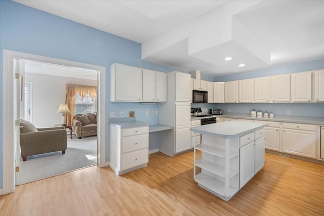 kitchen with a center island, white cabinets, light wood-type flooring, and black appliances