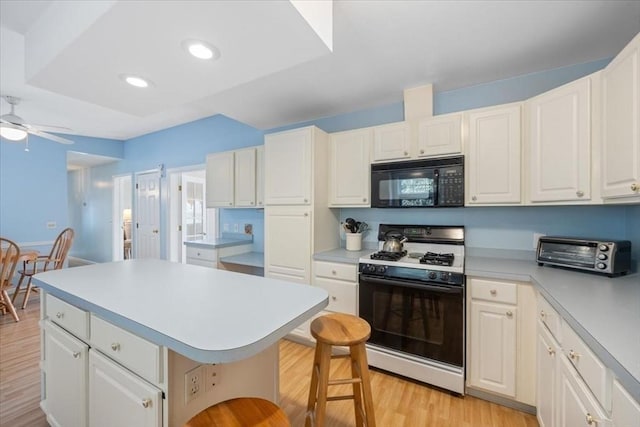 kitchen featuring a center island, a breakfast bar, white cabinets, and gas range oven