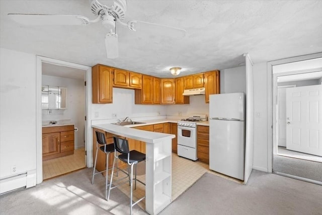 kitchen featuring sink, white appliances, a baseboard heating unit, a kitchen breakfast bar, and light carpet