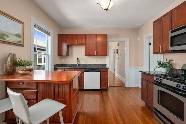 46 Farquhar Unit 2, Boston, MA 02131 - kitchen with stainless steel appliances, wood finished floors, a sink, a peninsula, and a wainscoted wall
