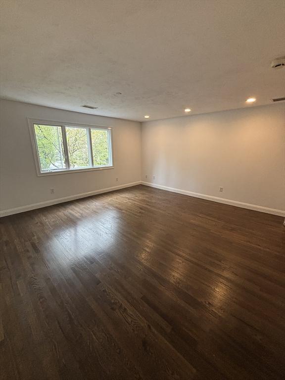spare room featuring baseboards and dark wood finished floors