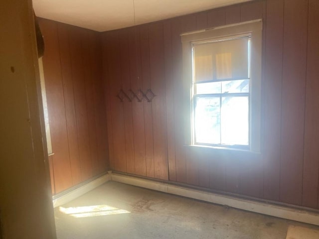 empty room featuring a baseboard heating unit and wooden walls