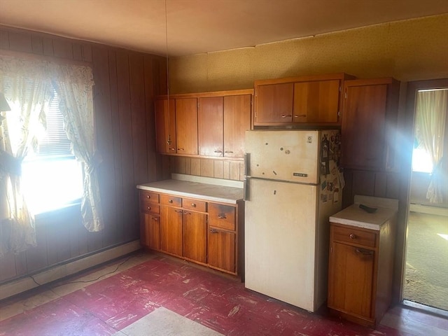 kitchen with wooden walls, baseboard heating, and white fridge