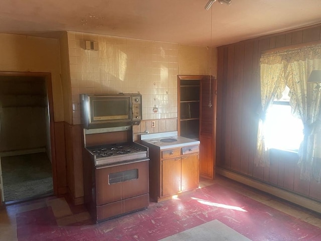 kitchen with range with gas stovetop and wooden walls