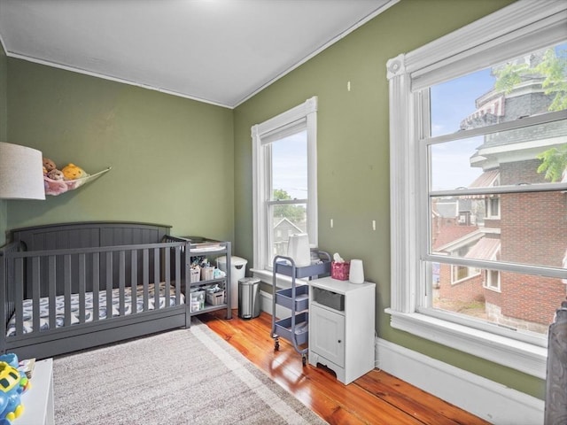 743 Bridge St, Lowell, MA 01850 - bedroom with multiple windows, wood finished floors, crown molding, and a crib