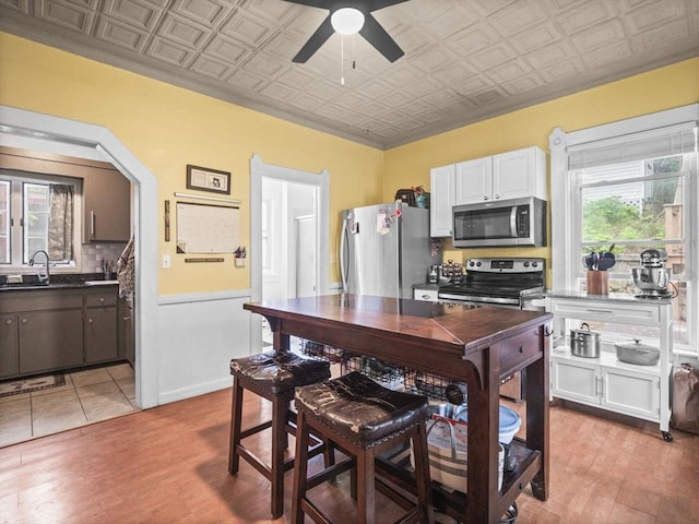 743 Bridge St, Lowell, MA 01850 - kitchen featuring appliances with stainless steel finishes, an ornate ceiling, ceiling fan, dark countertops, and light wood-type flooring