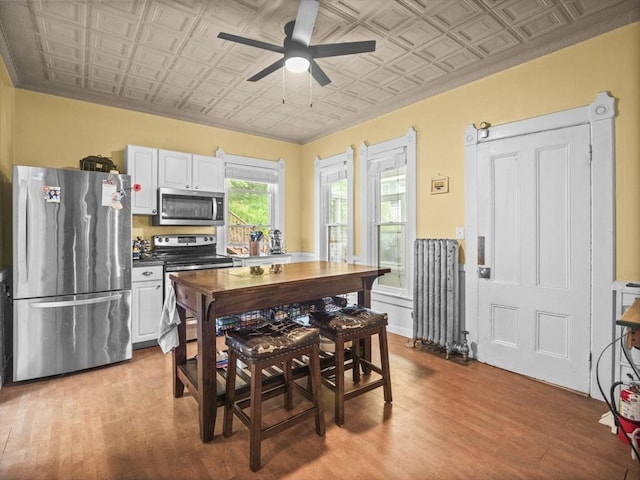 743 Bridge St, Lowell, MA 01850 - dining area featuring an ornate ceiling, a ceiling fan, wood finished floors, crown molding, and wainscoting