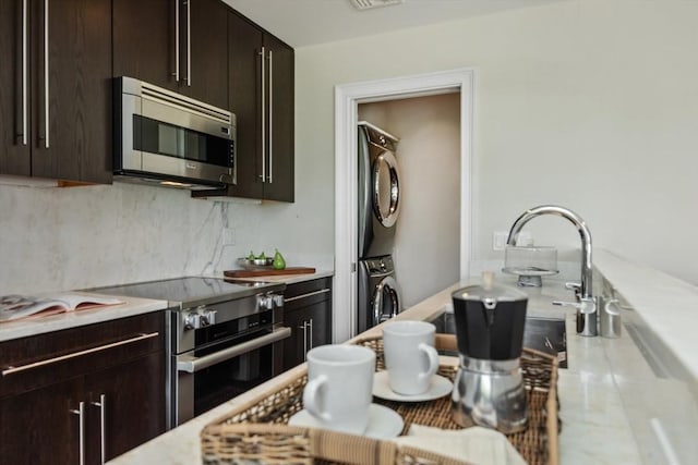 56 Commonwealth Ave Ph, Ph, Boston, MA 02116 - kitchen with stainless steel appliances, stacked washer / drying machine, light countertops, tasteful backsplash, and dark brown cabinetry