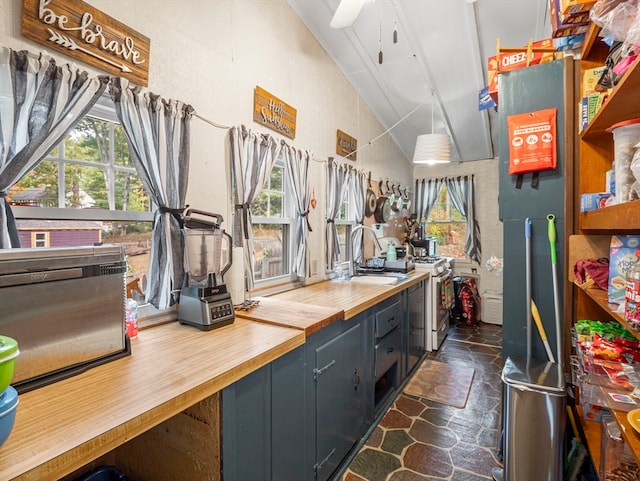 kitchen with lofted ceiling, gas range gas stove, sink, butcher block countertops, and ceiling fan