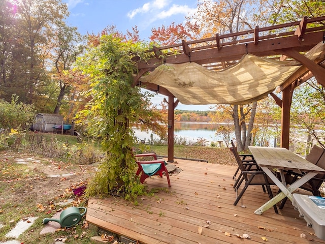 wooden terrace with a water view, a pergola, and a shed