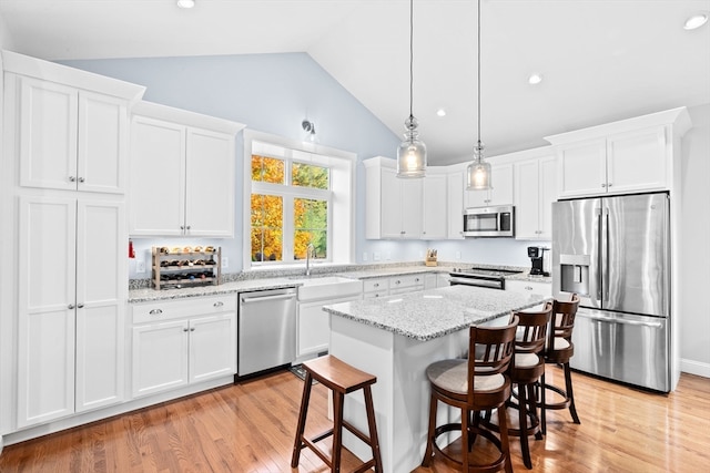 kitchen with vaulted ceiling, stainless steel appliances, and white cabinets