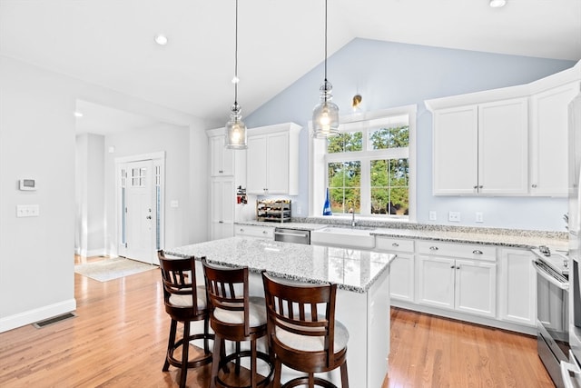 kitchen with a kitchen island, vaulted ceiling, light hardwood / wood-style flooring, and white cabinetry