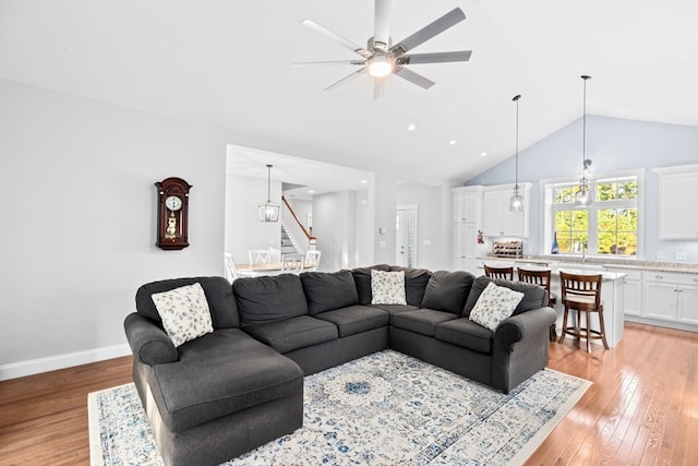 living room featuring sink, vaulted ceiling, light wood-type flooring, and ceiling fan