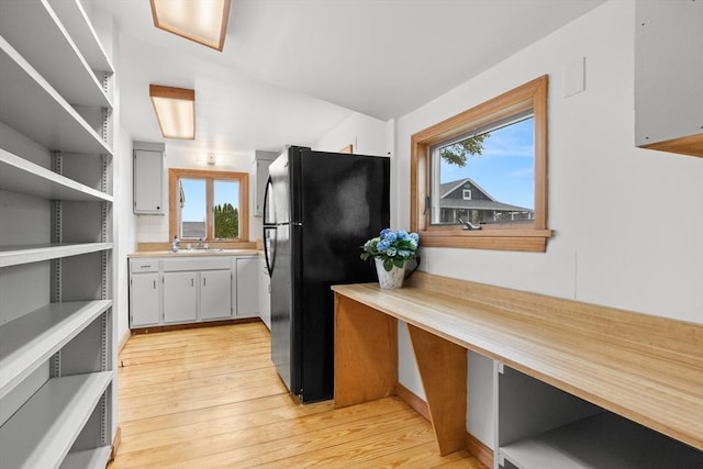 kitchen featuring freestanding refrigerator, a healthy amount of sunlight, light countertops, and a sink