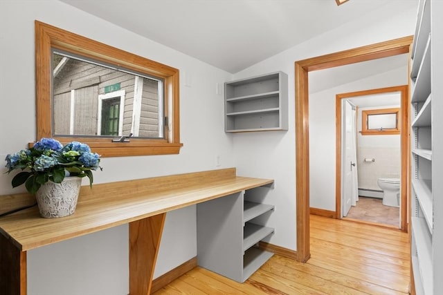 interior space featuring lofted ceiling, tile walls, baseboard heating, baseboards, and light wood-style floors