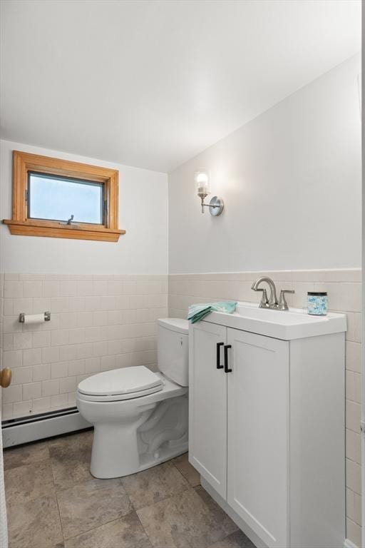 bathroom with wainscoting, tile walls, toilet, and baseboard heating