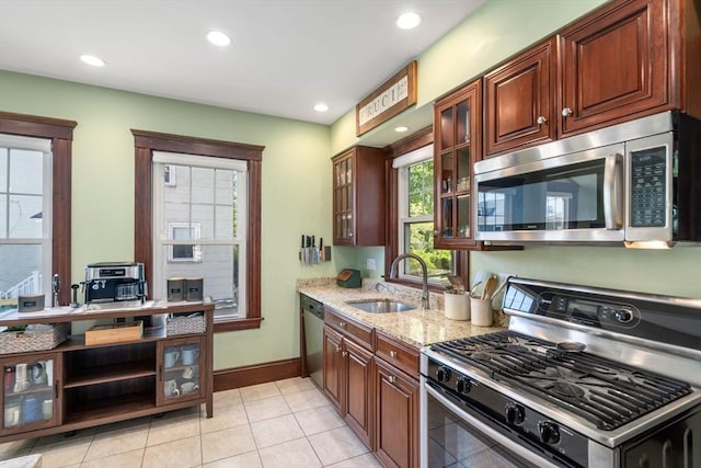kitchen featuring appliances with stainless steel finishes, light stone countertops, a sink, light tile patterned floors, and recessed lighting