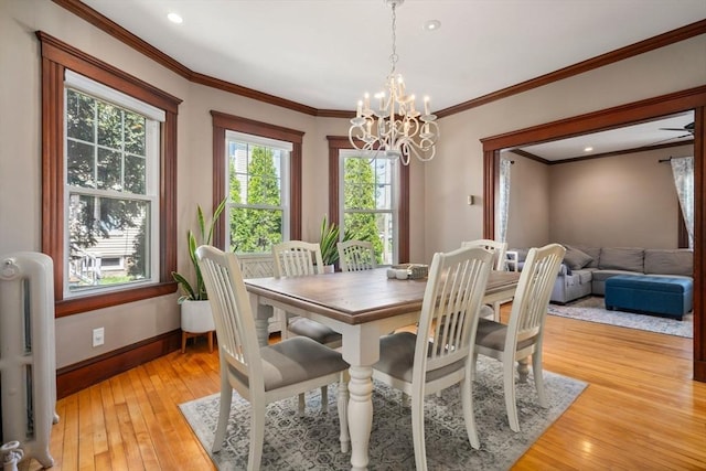 dining area featuring light wood-style floors, radiator heating unit, a wealth of natural light, and an inviting chandelier