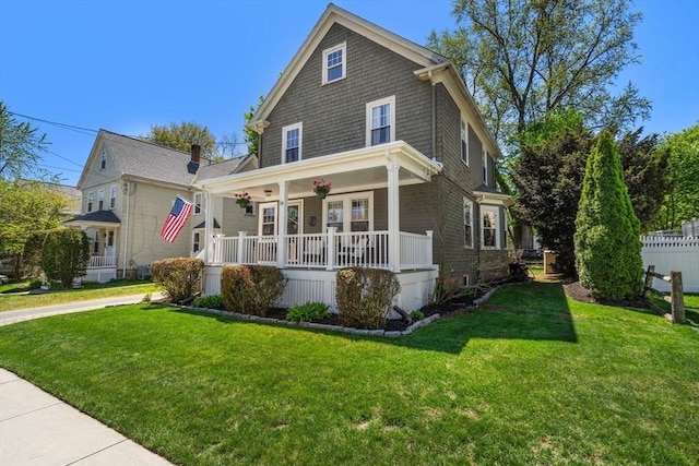 american foursquare style home featuring covered porch and a front lawn