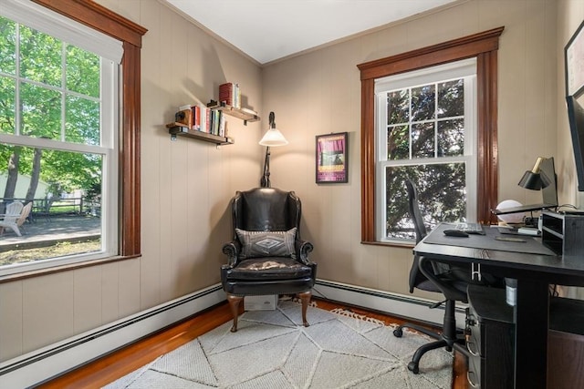 office area with plenty of natural light, a baseboard heating unit, and wood finished floors