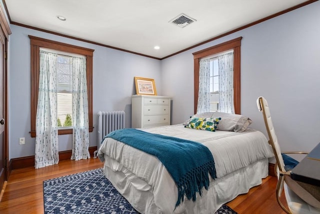 bedroom with visible vents, radiator, crown molding, and wood finished floors