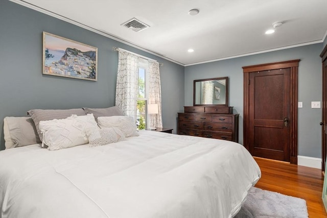 bedroom with crown molding, recessed lighting, baseboards, wood finished floors, and visible vents