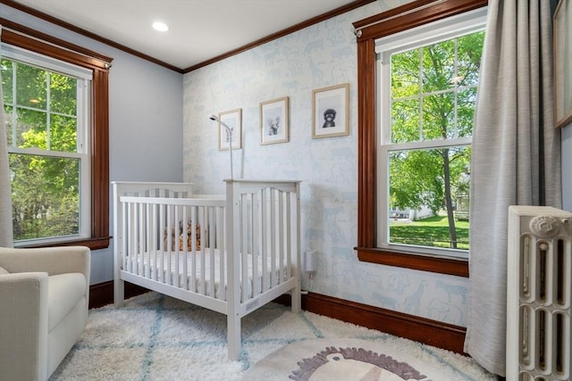 bedroom featuring crown molding, a nursery area, radiator heating unit, wallpapered walls, and baseboards