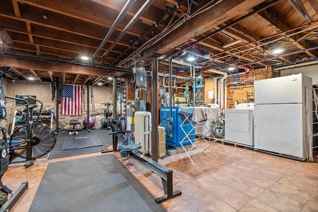 unfinished basement with freestanding refrigerator, a heating unit, gas water heater, and washer and dryer