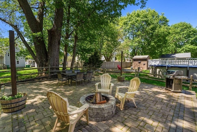 view of patio / terrace featuring outdoor dining space, an outdoor fire pit, a storage shed, grilling area, and an outbuilding