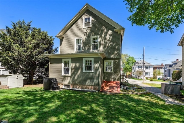 rear view of property featuring a storage shed, a yard, and an outbuilding