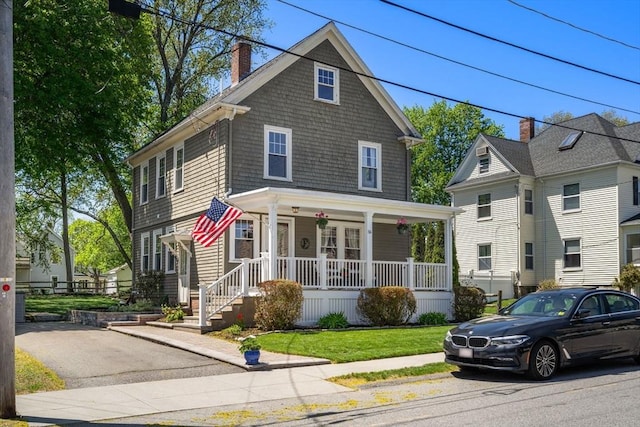 traditional style home featuring covered porch and a chimney