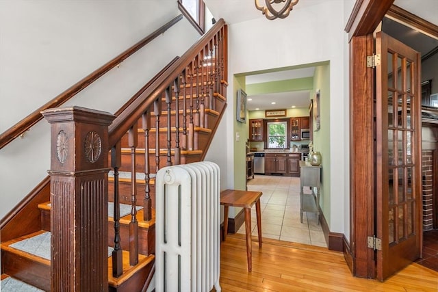 stairway with an inviting chandelier, radiator, and hardwood / wood-style flooring