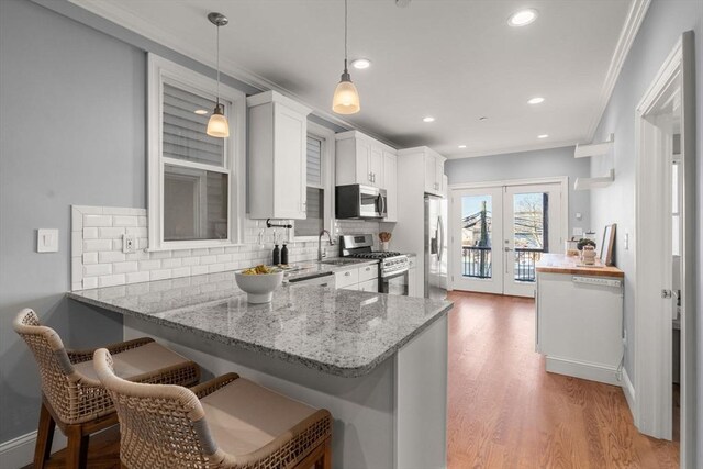 kitchen featuring light stone counters, white cabinets, french doors, backsplash, and stainless steel appliances