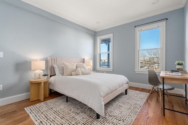 bedroom with baseboards, ornamental molding, and wood finished floors
