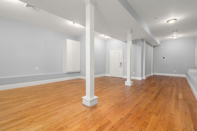 finished below grade area featuring baseboards, light wood-style flooring, and visible vents