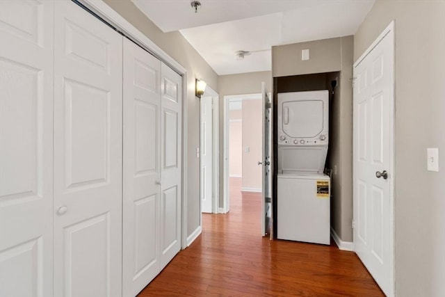 hallway with wood-type flooring and stacked washer and dryer