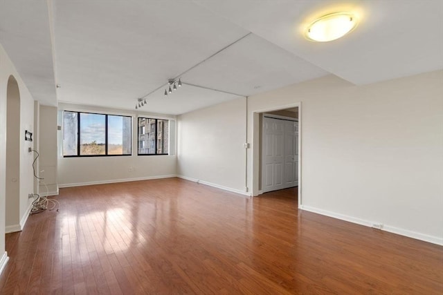 spare room featuring rail lighting and wood-type flooring