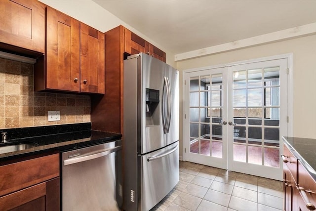 kitchen with french doors, dark stone counters, decorative backsplash, light tile patterned flooring, and appliances with stainless steel finishes