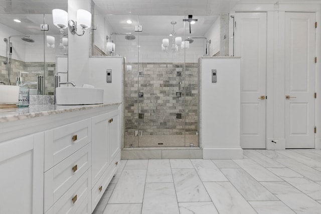 bathroom with a shower with door, vanity with extensive cabinet space, tile floors, and a notable chandelier