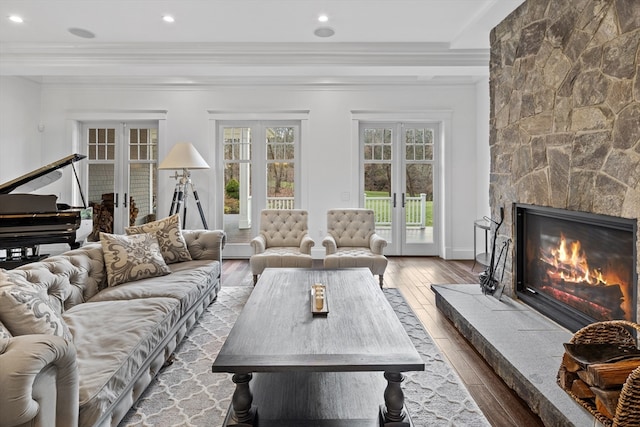 living room with french doors, ornamental molding, a large fireplace, and hardwood / wood-style floors