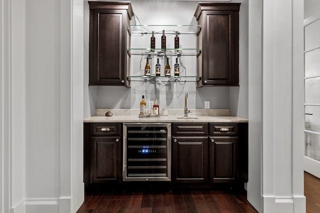 bar with beverage cooler, dark brown cabinets, and dark hardwood / wood-style flooring