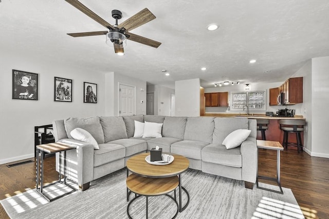 living room with sink, dark wood-type flooring, and ceiling fan