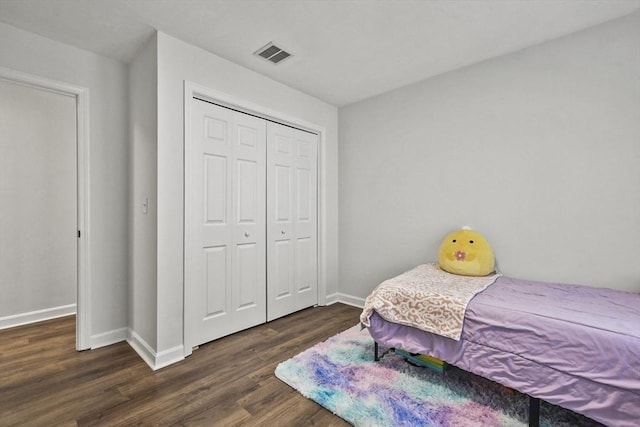 bedroom with dark hardwood / wood-style flooring and a closet