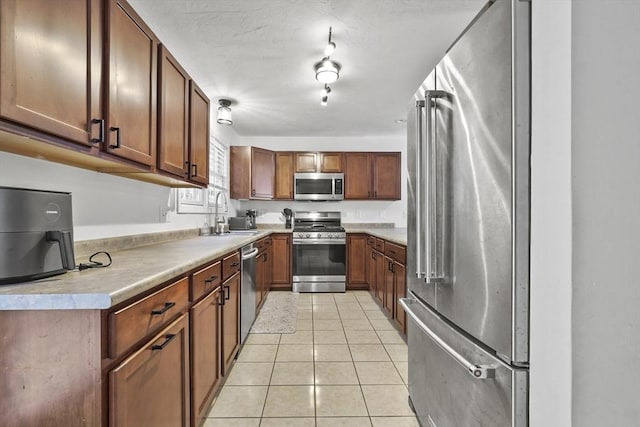 kitchen featuring stainless steel appliances, sink, and light tile patterned floors