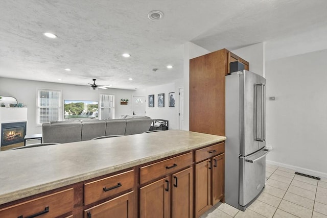 kitchen featuring ceiling fan, high quality fridge, light tile patterned floors, and a textured ceiling