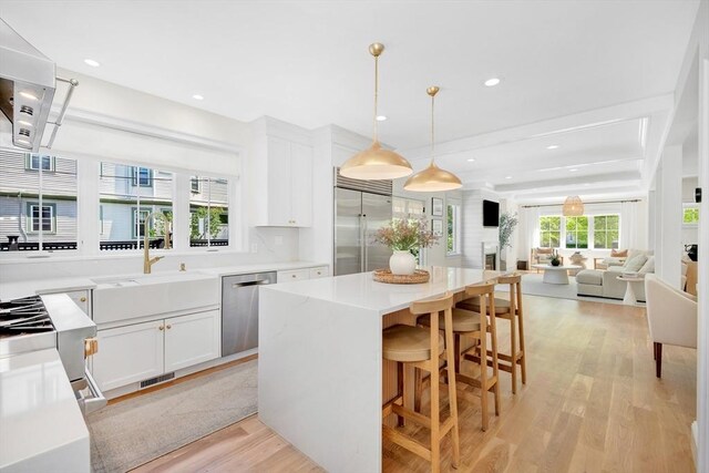 7 Newman St, Cambridge, MA 02140 - kitchen with stainless steel appliances, light wood-style floors, a sink, white cabinetry, and recessed lighting
